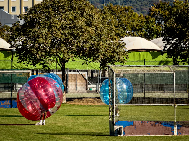 Twee spelers in opblaasbare bumperballen op een grasveld